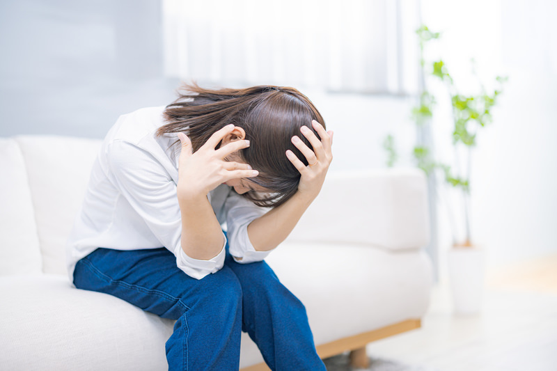 頭が痛くてうずくまる女性の無料の写真素材